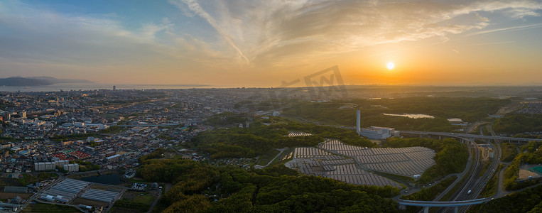 太阳落山在不断扩张的城市边缘的小型能源厂的太阳能电池板上