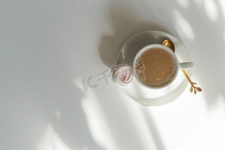 免费观影摄影照片_白咖啡杯中的咖啡，茶碟上的蛋白酥皮，白色桌子上，阳光下空旷的空间，叶影，产品背景，3D 放松。