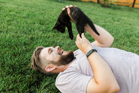 有小猫躺在草地上玩耍的男人 — 友谊爱动物和宠物主人的概念