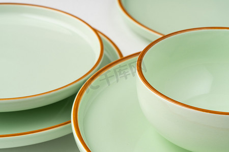 淡绿色卷轴摄影照片_一套带橙色轮廓的淡绿色陶瓷餐具