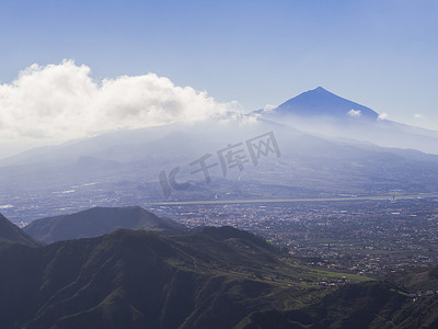 皮科德尔泰德火山蓝色山顶云中西班牙最高山峰，可欣赏拉奥罗塔瓦市和绿色山丘、特内里费加那利岛、蓝天背景