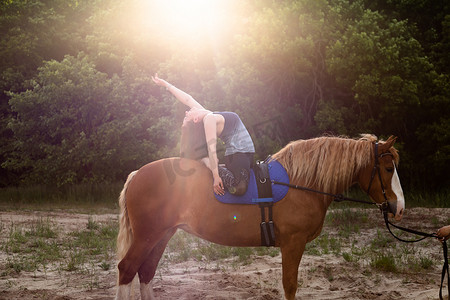 在树木的背景下骑马做瑜伽的年轻女子
