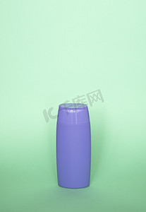 淡绿色背景上的紫罗兰色空白洗发水瓶或沐浴露。