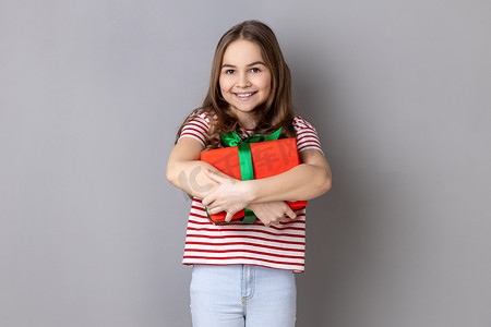 小女孩穿着条纹 T 恤拥抱礼物庆祝生日，节日礼盒