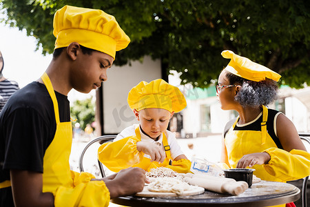 身着黄色厨师帽和围裙制服的非洲黑人和白人儿童的多国儿童的童年厨师活动。
