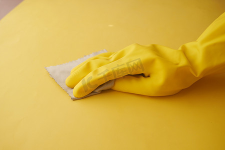 手拿喷雾摄影照片_手拿黄色橡胶手套用布清洁桌子