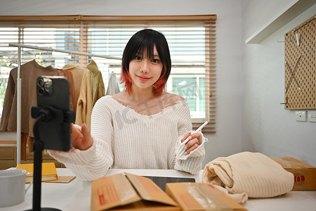 亚洲女性在线卖家所有者使用智能手机在网上商店查看客户订单的照片