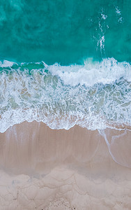 俯瞰水摄影照片_在普吉岛自由海滩的热带海滩上俯瞰波浪和蓝色海洋无人机鸟瞰图