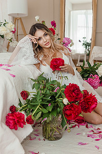 家里一个穿着白色睡衣的漂亮女孩，在一张大床上被春天的花朵包围着。