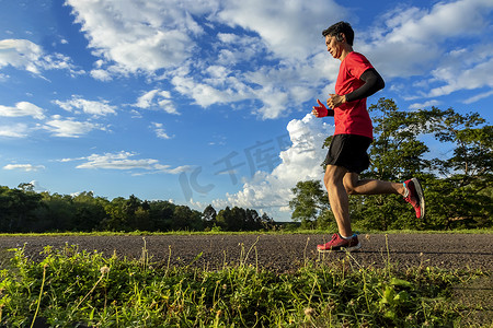 英俊的年轻人在一条乡村道路上为身体健康奔跑
