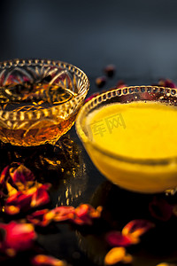 玻璃碗中黑色光滑表面上的 Ayurvedic 保湿面膜，配有一些酥油或澄清黄油、蜂蜜和包装。