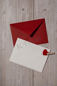 红色邀请卡摄影照片_问候卡或邀请卡模拟与木制背景上的红色信封。