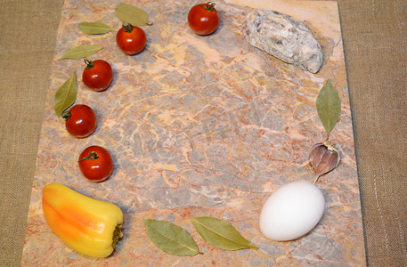 大理石表面上的蔬菜、鸡蛋和牡蛎壳，有自由空间：樱桃番茄、甜椒、大蒜和月桂叶