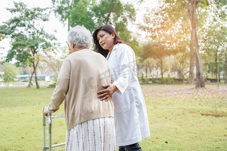 帮助和照顾亚洲老年或老年老妇人在愉快的新鲜假期里在公园散步时使用健康强壮的助行器。