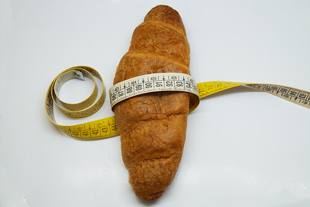 羊角面包上包裹着柔软的测量尺，作为不健康营养的象征