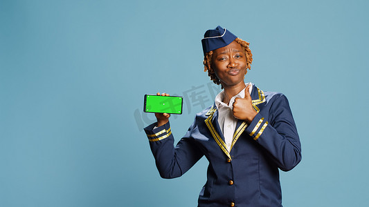 拿着有绿屏的智能手机的年轻空姐
