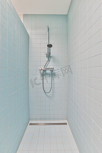 洗马桶摄影照片_在一间铺有白色瓷砖的蓝色房间里淋浴