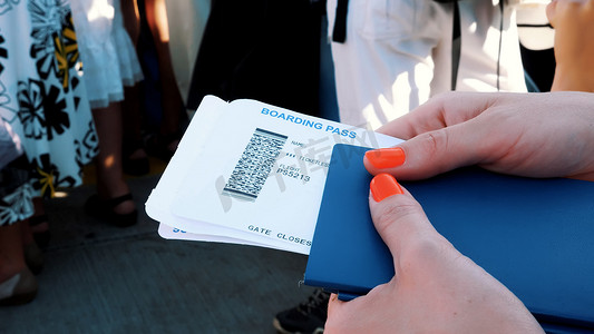 特写镜头，女性手拿着航空公司登机牌票、登机牌和护照在机场