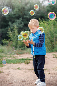 一个快乐的男孩抓住了一个心形的肥皂泡，一个孩子在公园里玩耍，轻气球漂浮在空中