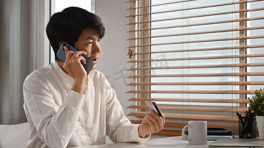 帅气的亚洲男人，有信用卡，在手机上聊天，连接到手机银行服务