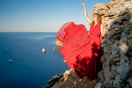 在大海的映衬下，一位身着红色飞裙的女子在风中飘扬。