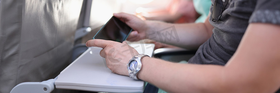飞机火车摄影照片_拿着智能手机的人手坐在飞机或火车的机舱里