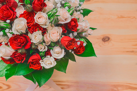 木地板背景上带绿叶的白玫瑰和红玫瑰的婚花