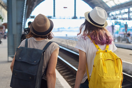 两个母亲和十几岁的女儿在火车站带着行李走路