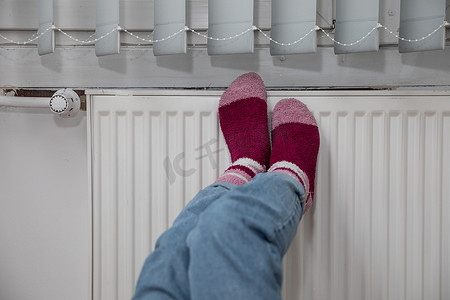 散热器摄影照片_在热散热器上加热冰冷的脚。