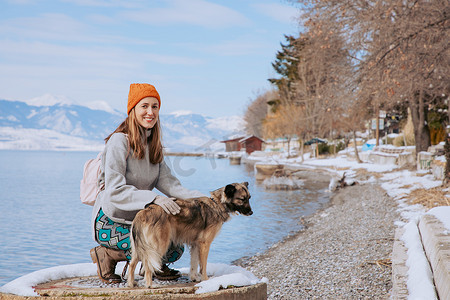 遛狗的女人摄影照片_冬天在湖岸遛狗的女人
