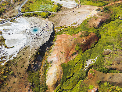 strokkur摄影照片_冰岛 Strokkur 温泉和间歇泉周围生机勃勃的绿地