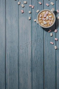 蓝色心空摄影照片_空的问候语或邀请卡模拟了白色的咖啡和棉花糖在木制的蓝色背景。
