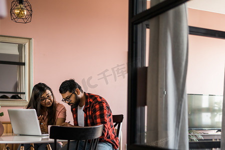 年轻的千禧一代印度夫妻做家庭文书工作、会计工作和审查纸质账单、笔记本电脑收据、使用在线计算器并在互联网上支付抵押贷款租金 — 经济危机概念
