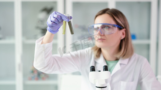 女科学家化学家在实验室比较试管与油和受污染的柴油燃料