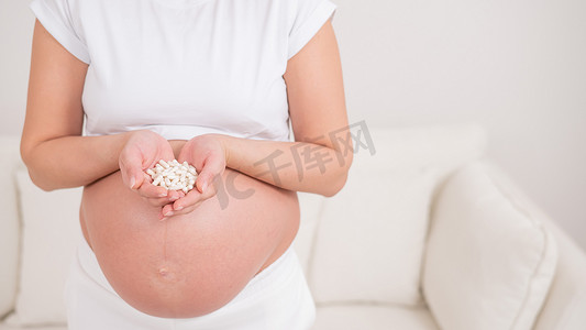 一个不露面的孕妇拿着一把白色药丸。