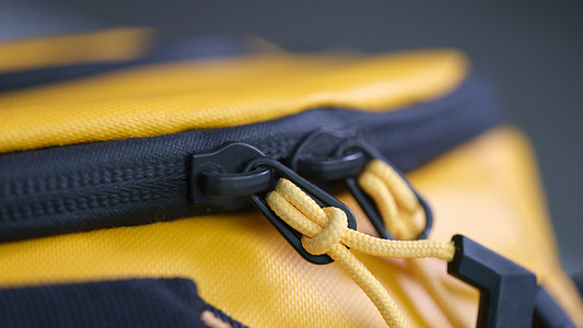 黄色时尚摄影照片_黄色背包特写上带绳索的拉链锁