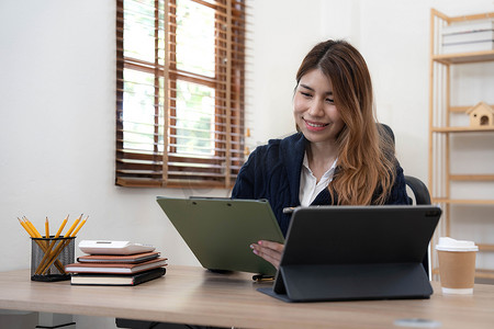 亚洲女性使用笔记本电脑，在办公室工作，在办公桌上使用计算器文档，进行规划分析财务报告、商业计划投资、财务分析概念。
