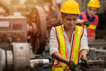 美国黑人女性青少年工人在工业工厂用重型钢机做兼职工作。