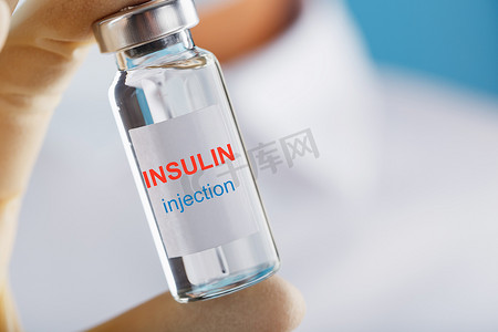 医生拿着一个注射器和一个装有胰岛素的安瓿，用于治疗糖尿病