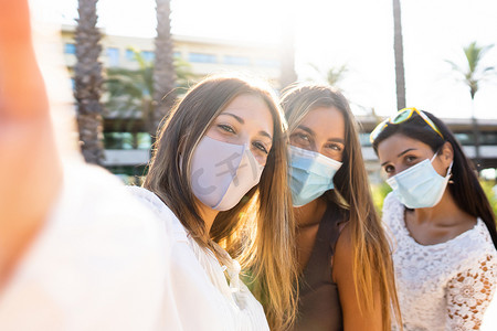 可爱的金发年轻女性与她的两个戴着冠状病毒防护面具的女性朋友自拍 — Covid-19 大流行的新正常生活使用社交网络连接