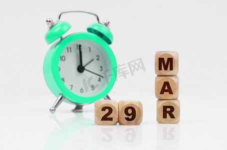 在白色背景上，一个绿色闹钟和一个带有铭文的日历 — 3 月 29 日