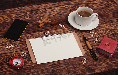 文字love摄影照片_一杯咖啡、笔记本、墨水笔、电话和木质背景中的木质文字 Love