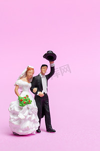 微型人婚礼，新娘和新郎夫妇在粉红色 backg