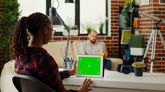 平板电脑绿幕摄影照片_使用带水平绿屏的数字平板电脑的年轻企业家