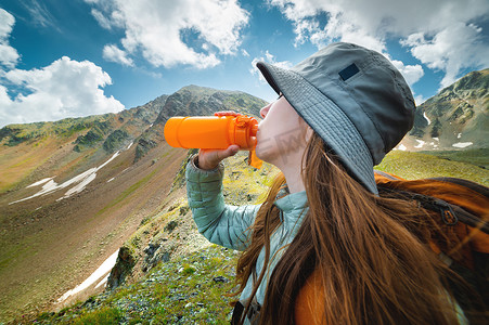 健康的女性徒步旅行者在大自然中徒步旅行时喝水。