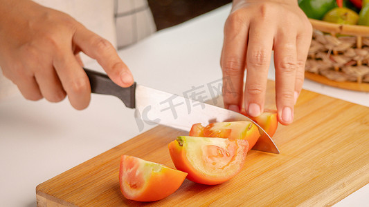 女人用刀在木排上把新鲜番茄切成碎片