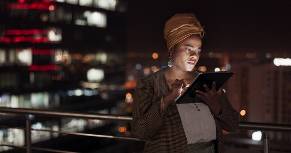 平板电脑、夜晚和阳台，一位商务黑人女性在她的办公室户外工作时正在做研究。