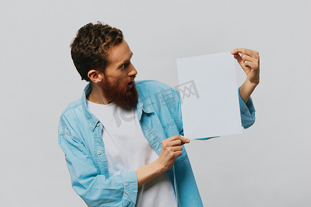 灰色背景中一位成年男性的肖像，手里拿着一张白纸，供您设计和文字、布局、复制空间、文字空间、指点