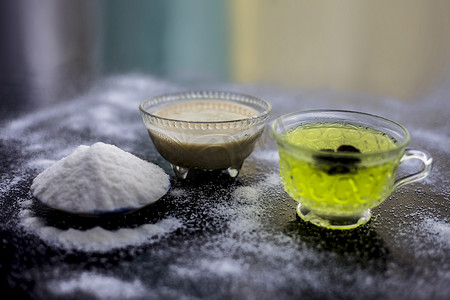 绿色面膜摄影照片_木质表面上的米粉和米粒，以及透明玻璃杯中的一些绿茶和八角茴香。用于治疗更光滑皮肤的面膜。