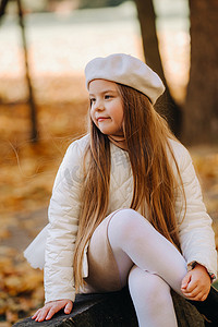温情情绪摄影照片_一个戴着帽子的快乐女孩在秋天的公园里散步